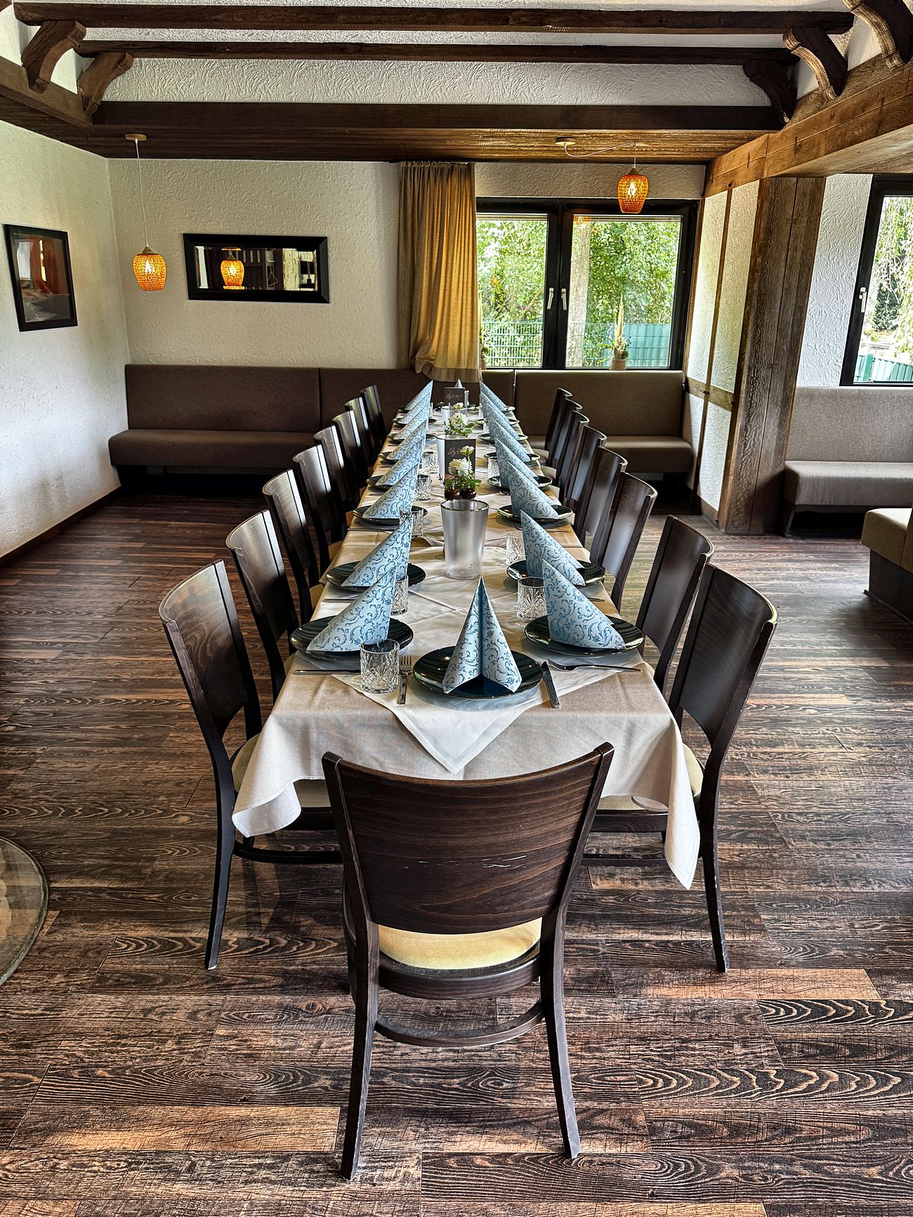 Eine lange eingedeckte Tafel im Saal unter Fachwerkbalken, mit gefalteten Servietten für eine große Gesellschaft